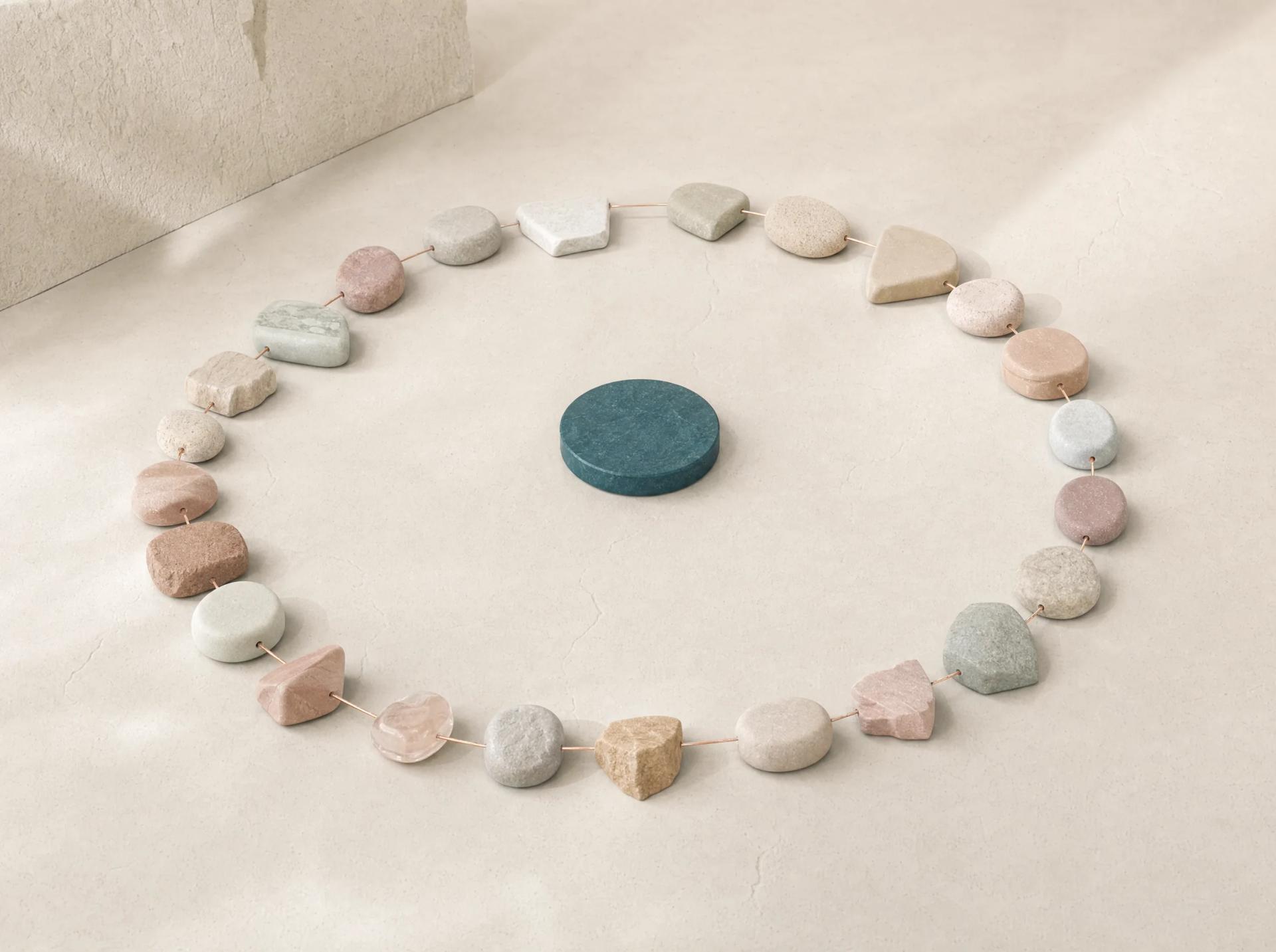 A circle of varied small stones organised around one shared teal centre.