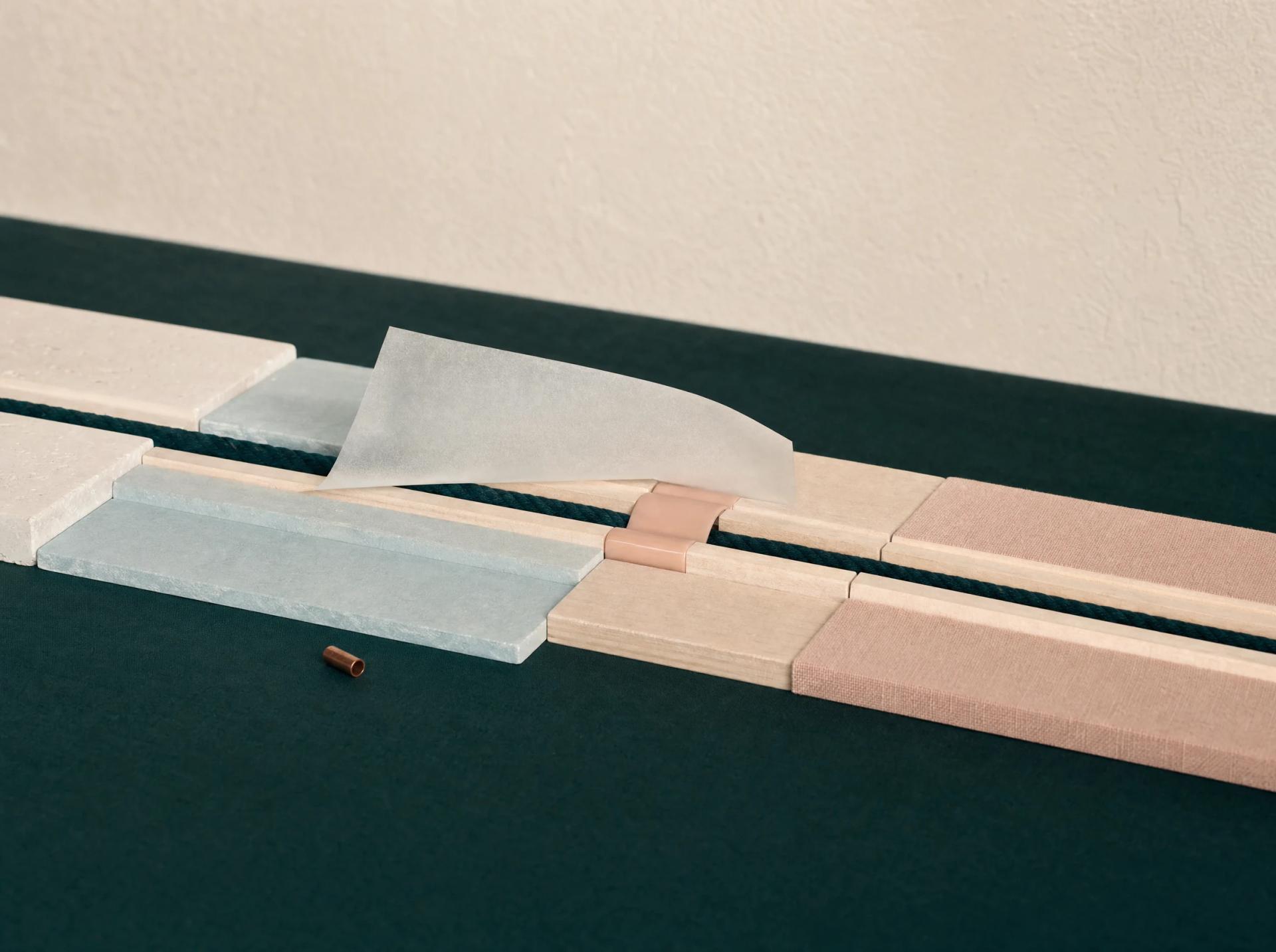 Teal cord carries a folded sheet through joined timber, mineral and textile sections of a diagnostic track.