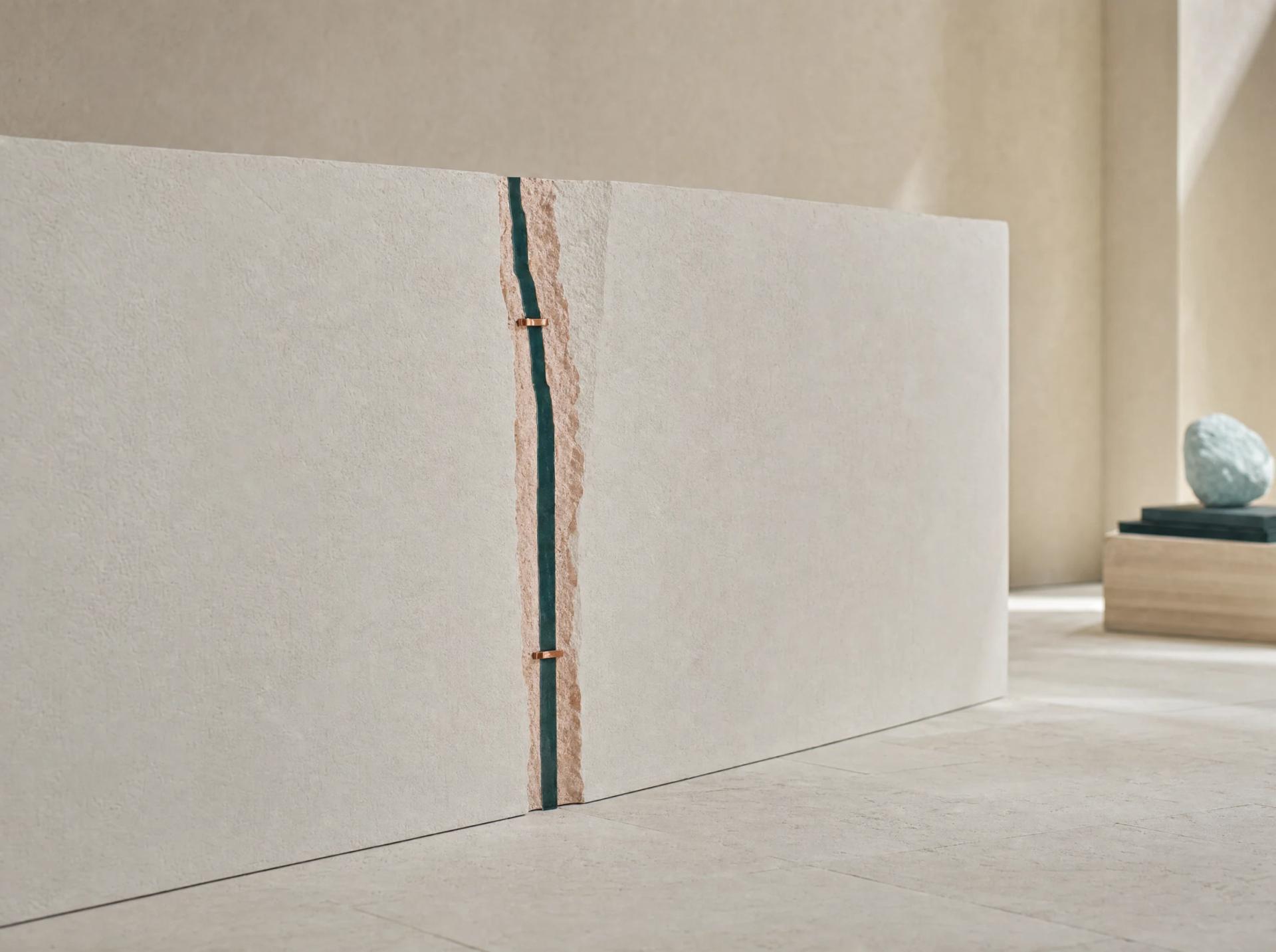 Two pale architectural planes meet at an exposed blush-and-teal seam secured with small copper ties.