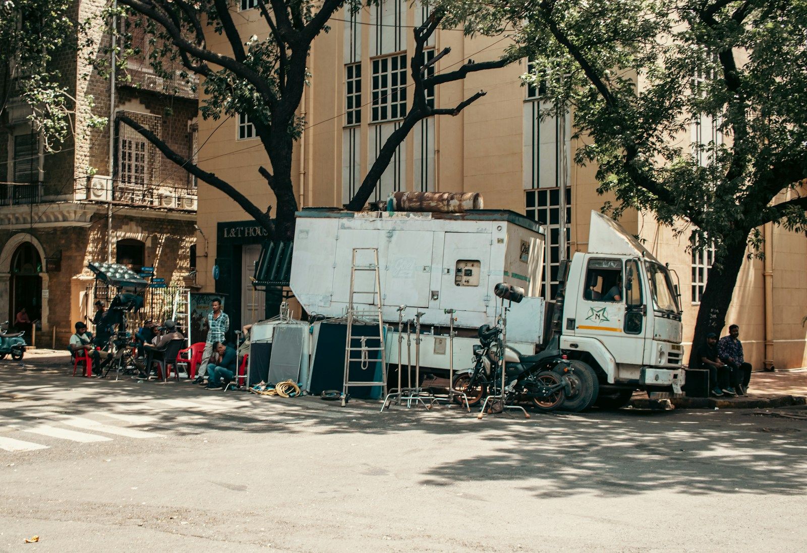 Production truck with equipment parked beside a building during a film setup