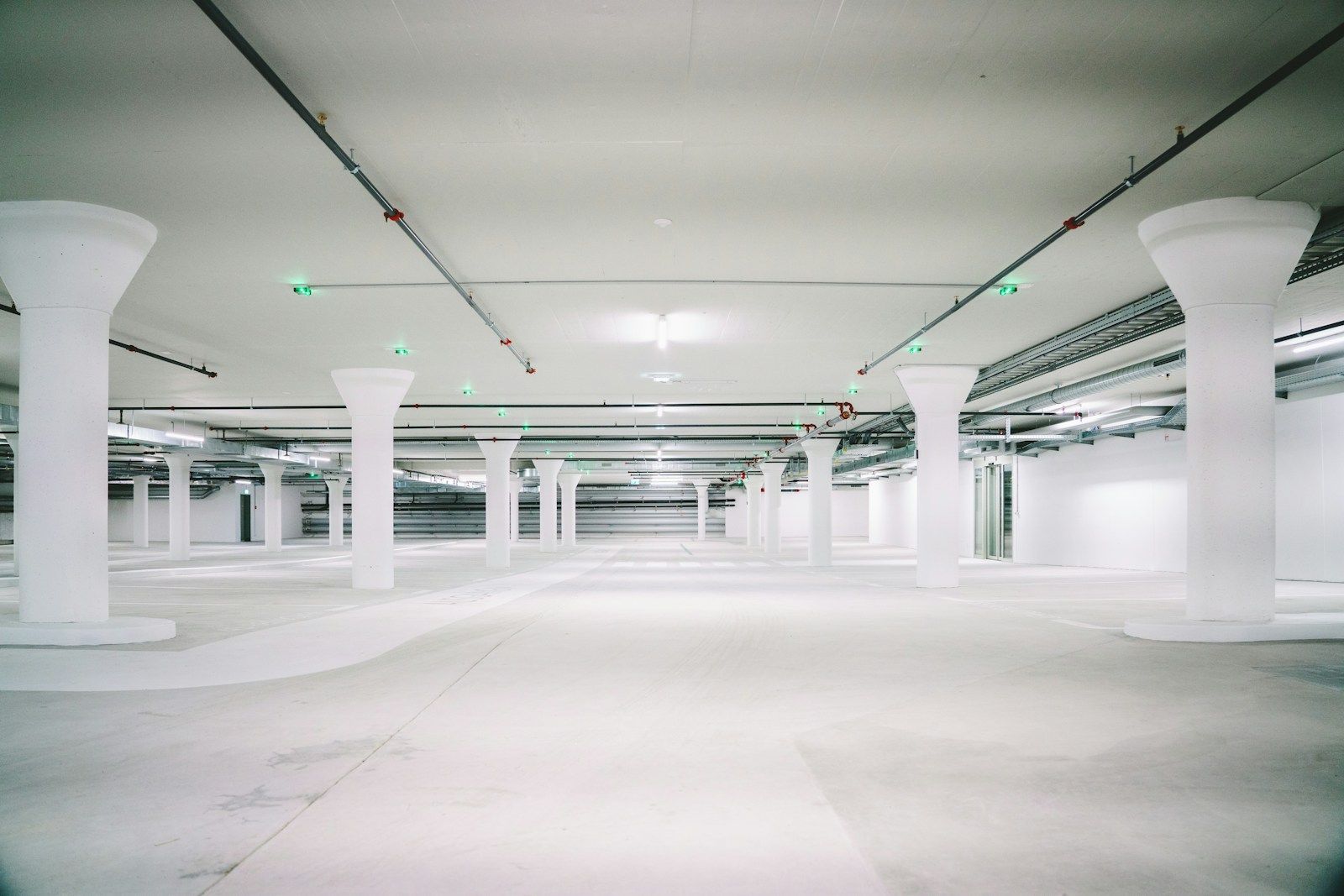 Empty concrete parking garage with white pillars and open driving lanes