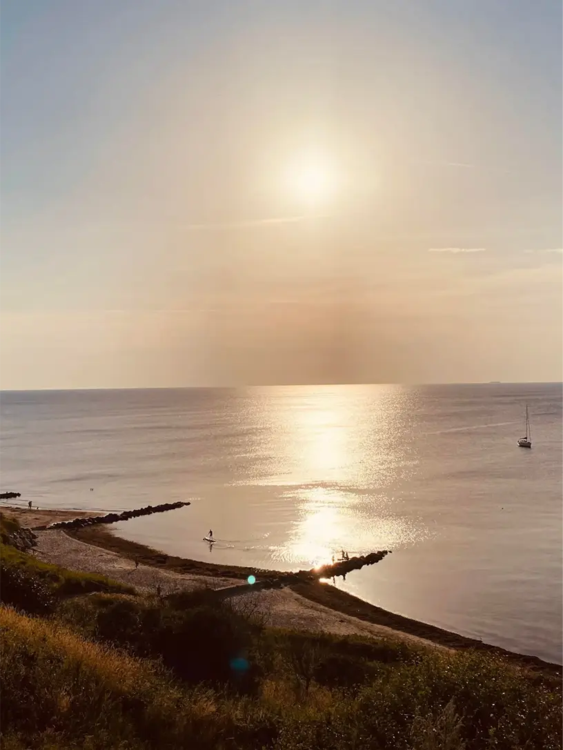Solen er ved at gå ned over et sommerhus ved vandet.