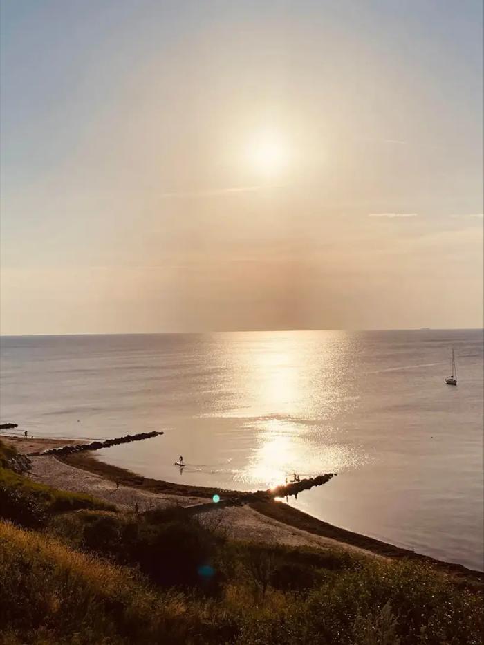 Solen er ved at gå ned over et sommerhus ved vandet.
