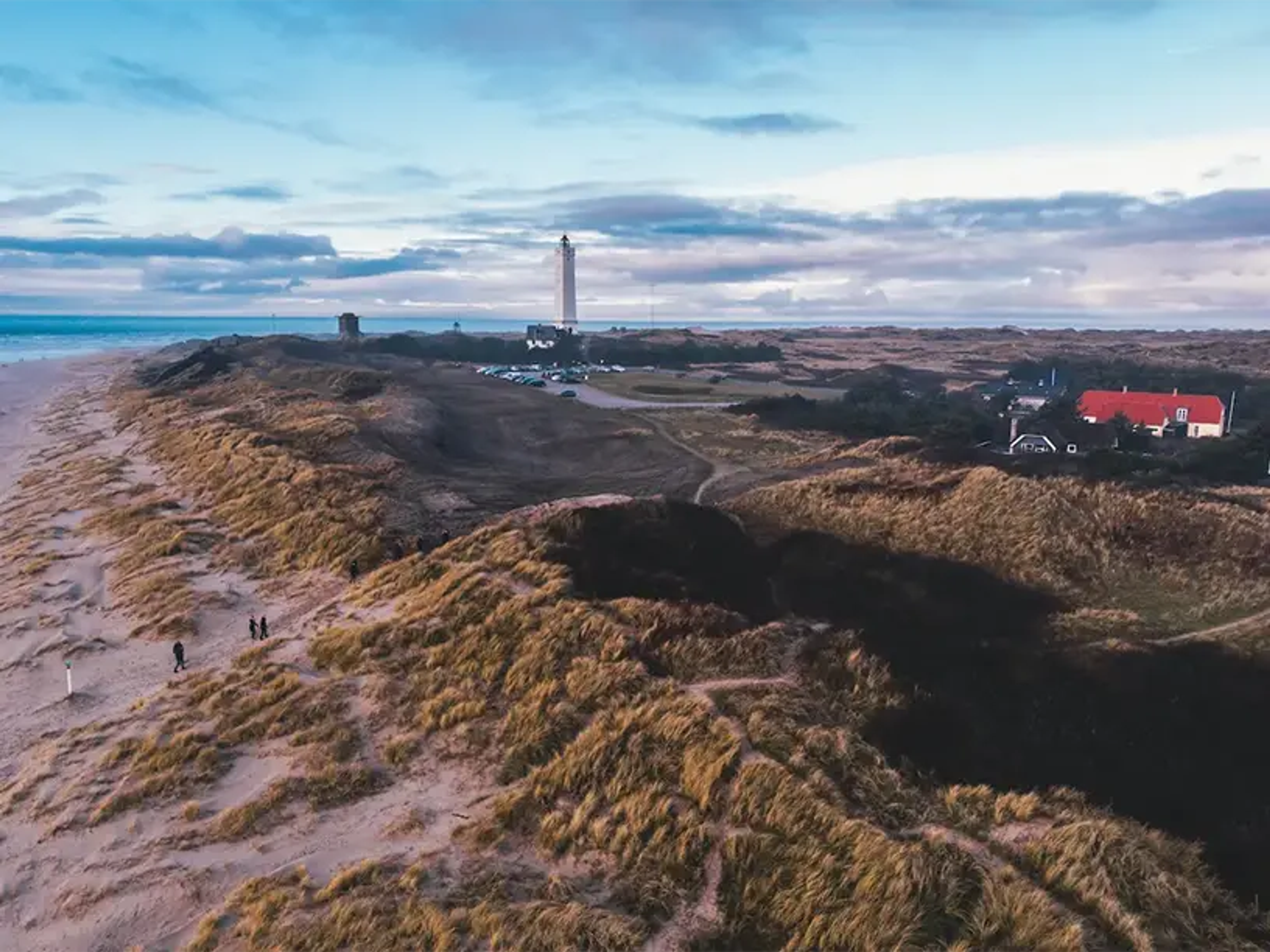 En luftfoto af en strand med klitter og et fyrtårn giver inspiration til dem, der søger lån til sommerhus eller sommerhus lån.