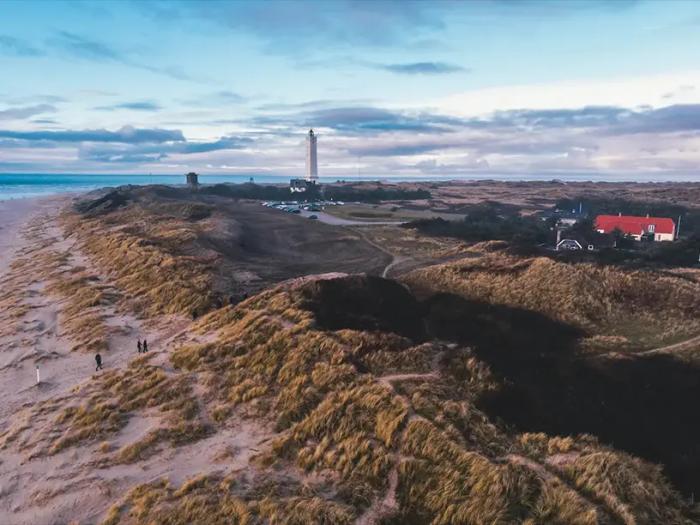 En luftfoto af en strand med klitter og et fyrtårn giver inspiration til dem, der søger lån til sommerhus eller sommerhus lån.