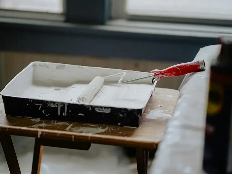 Malerrulle og bakke med hvid maling klar til boligrenovering.