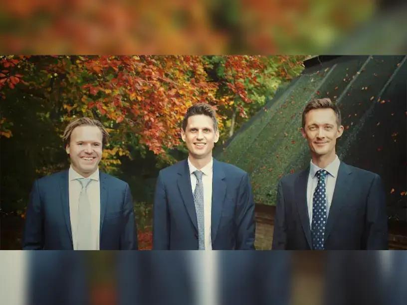 Tre mænd i jakkesæt diskuterer finansieringsmuligheder for et byggeprojekt.