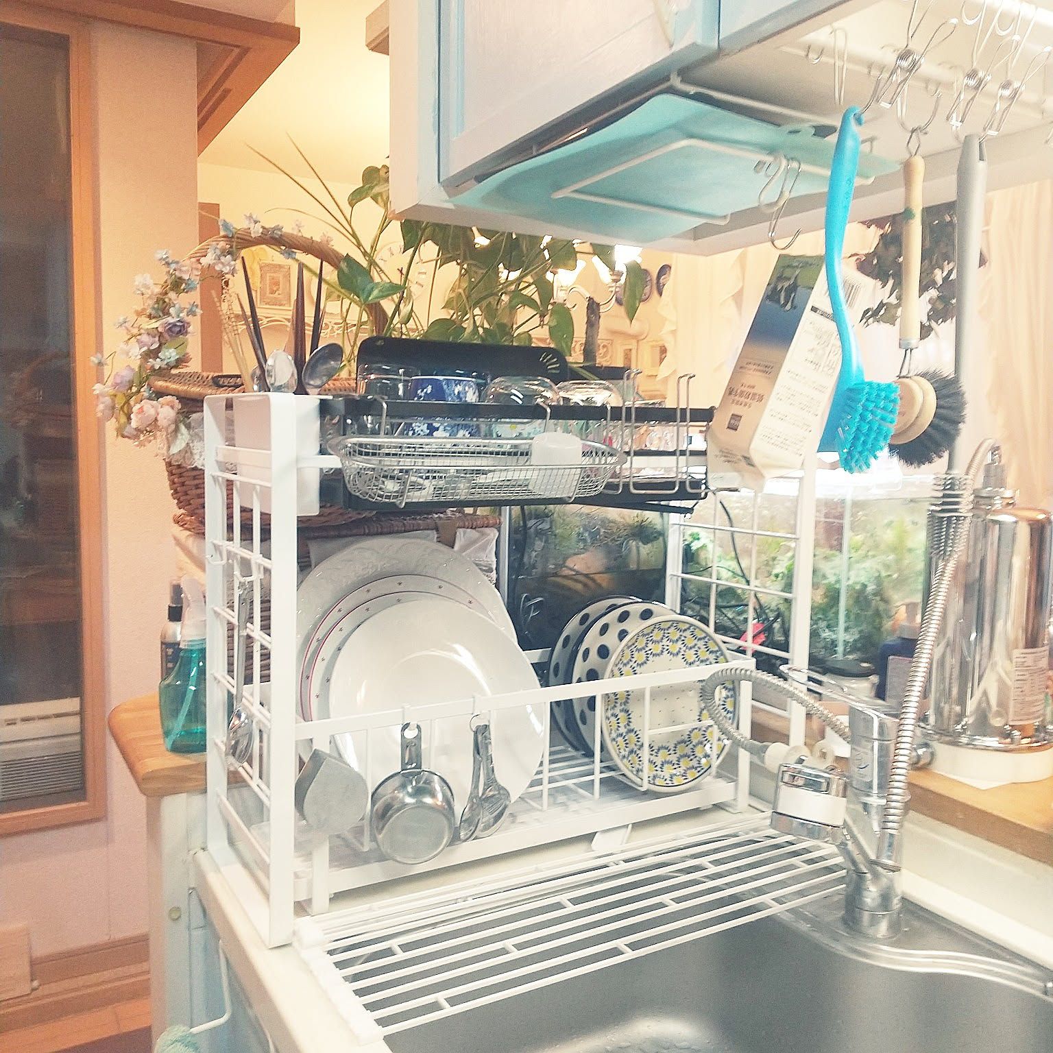 A Yamazaki Tower dish rack holding plates, cups, and kitchen tools above a compact sink.