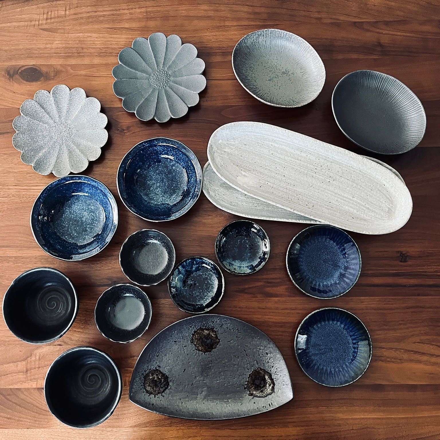 Japanese small plates and serving dishes arranged on a wooden table.