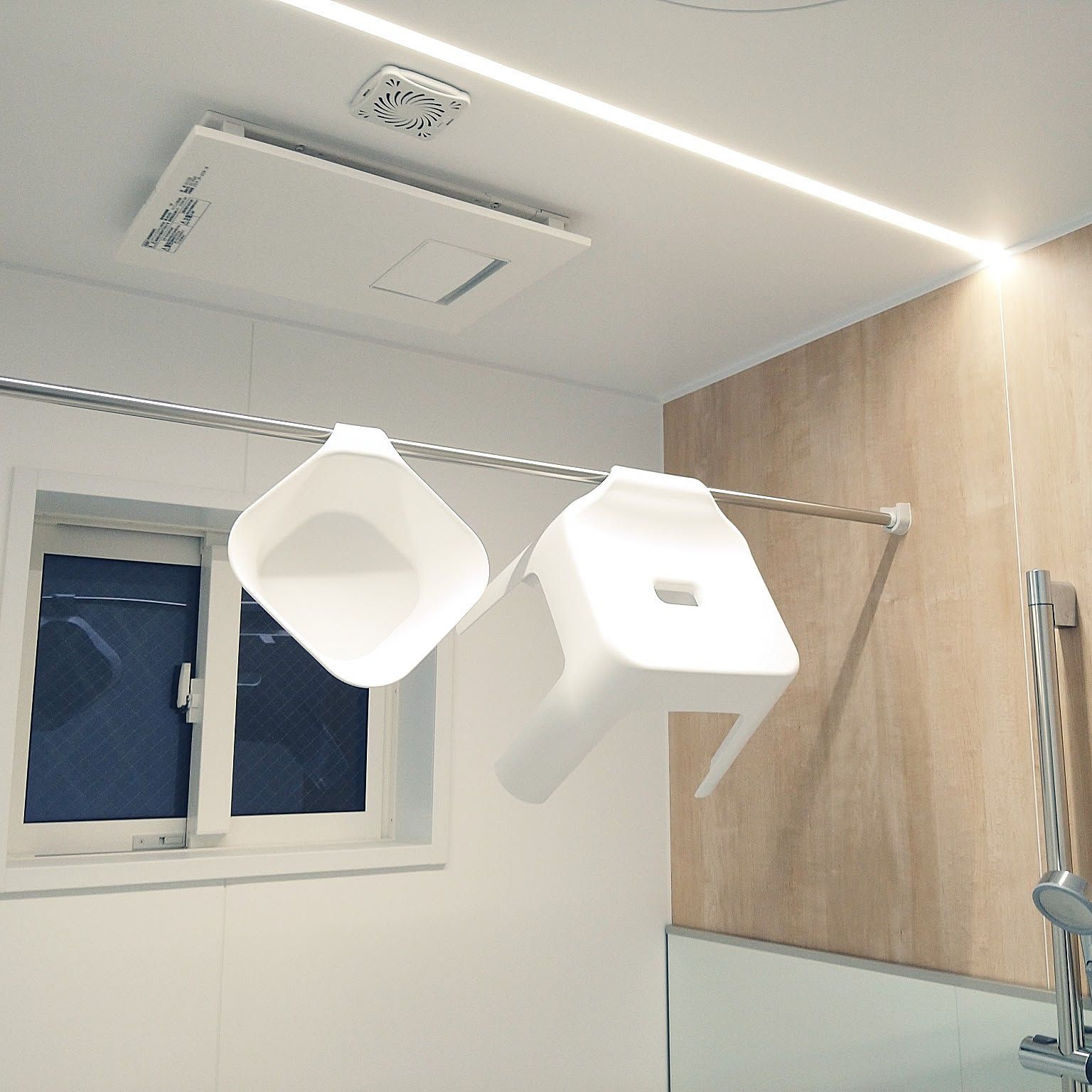 White Japanese bath stool and wash bucket hanging from a bathroom drying bar.