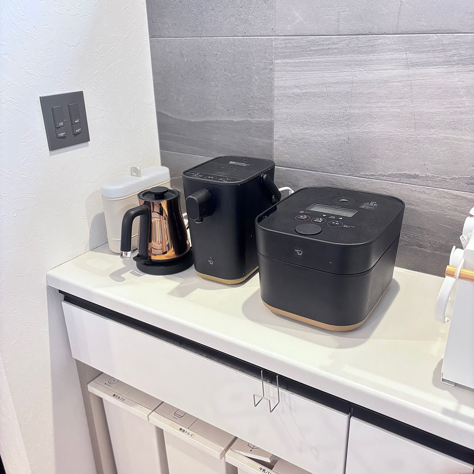 A black Zojirushi STAN. rice cooker and matching electric pot arranged on a clean kitchen counter.