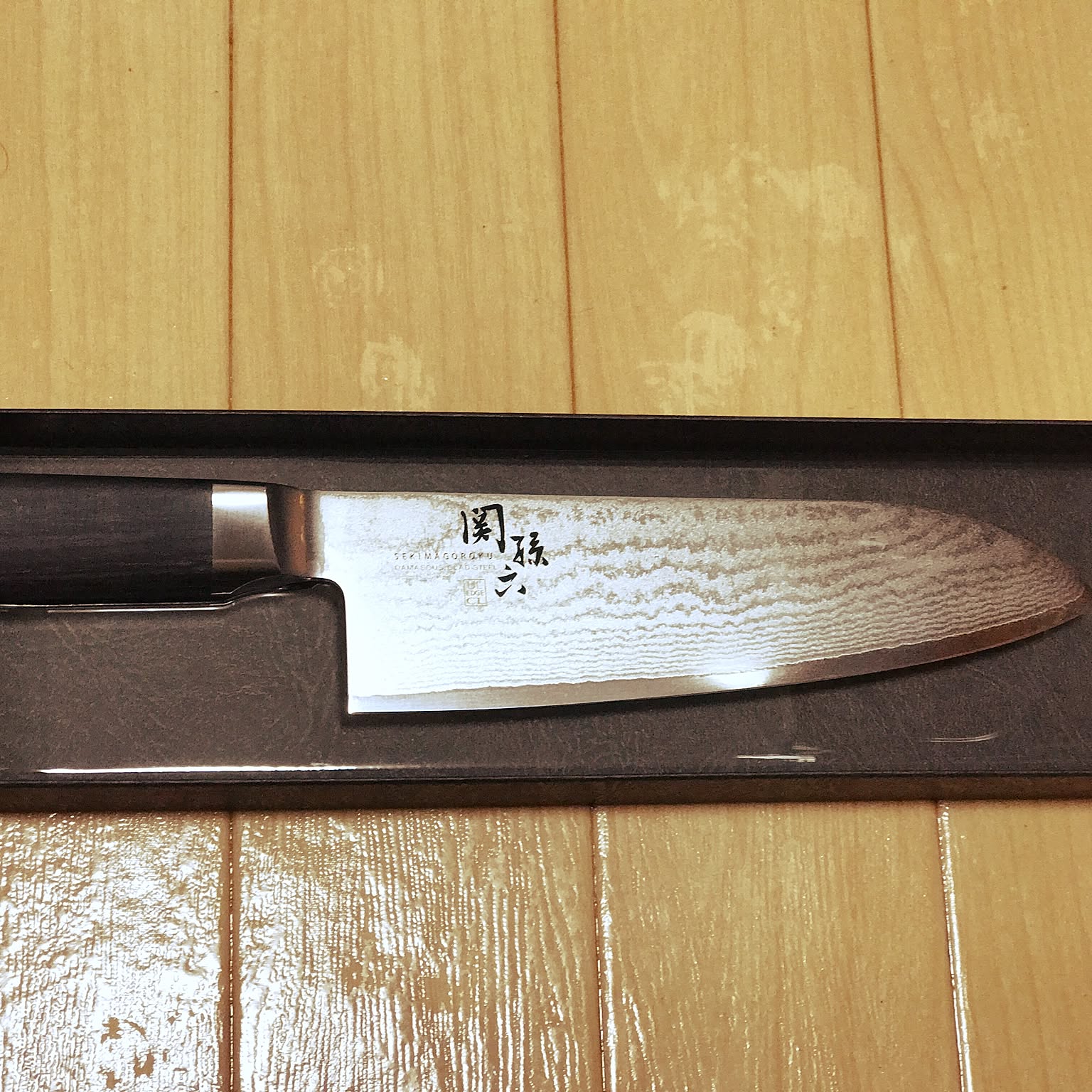 Close-up of a Japanese santoku blade showing the wave pattern along the clad steel