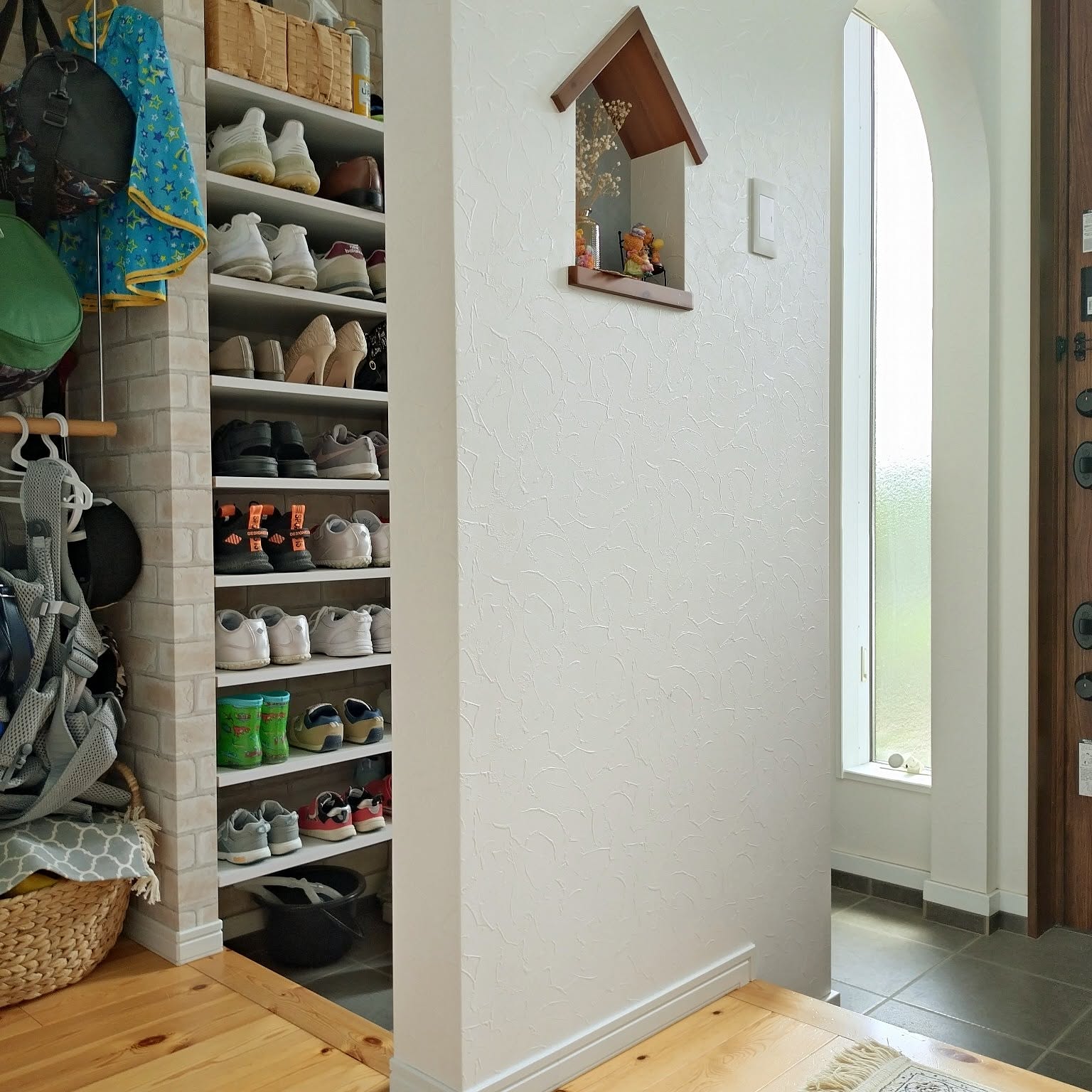 A Japanese entryway with open shoe shelves, bags, and a clear walking path beside the front door.