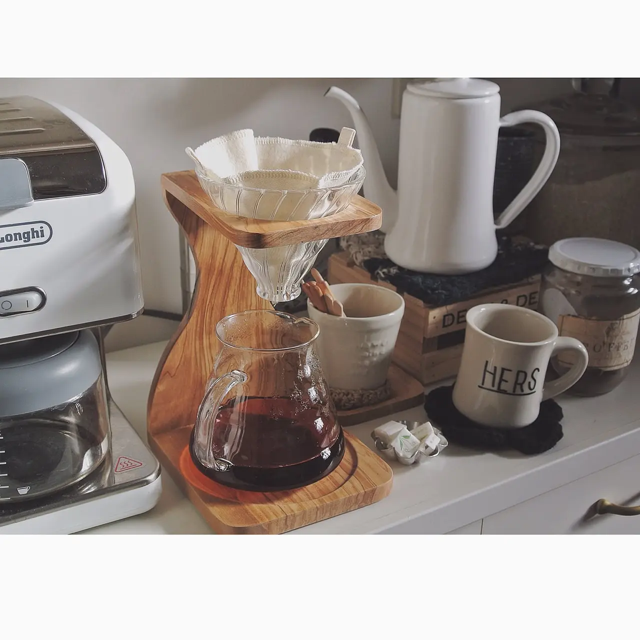 A Hario V60 olive-wood stand with kettle and coffee tools on a bright kitchen counter.