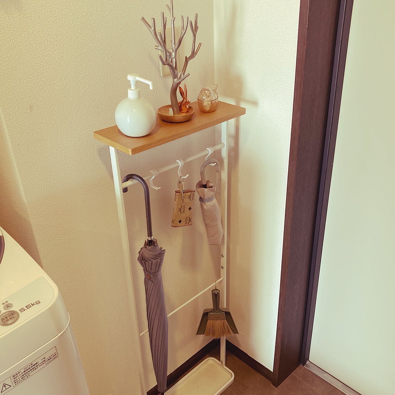 A narrow Japanese apartment entryway with slim wall-side storage for umbrellas and daily items.