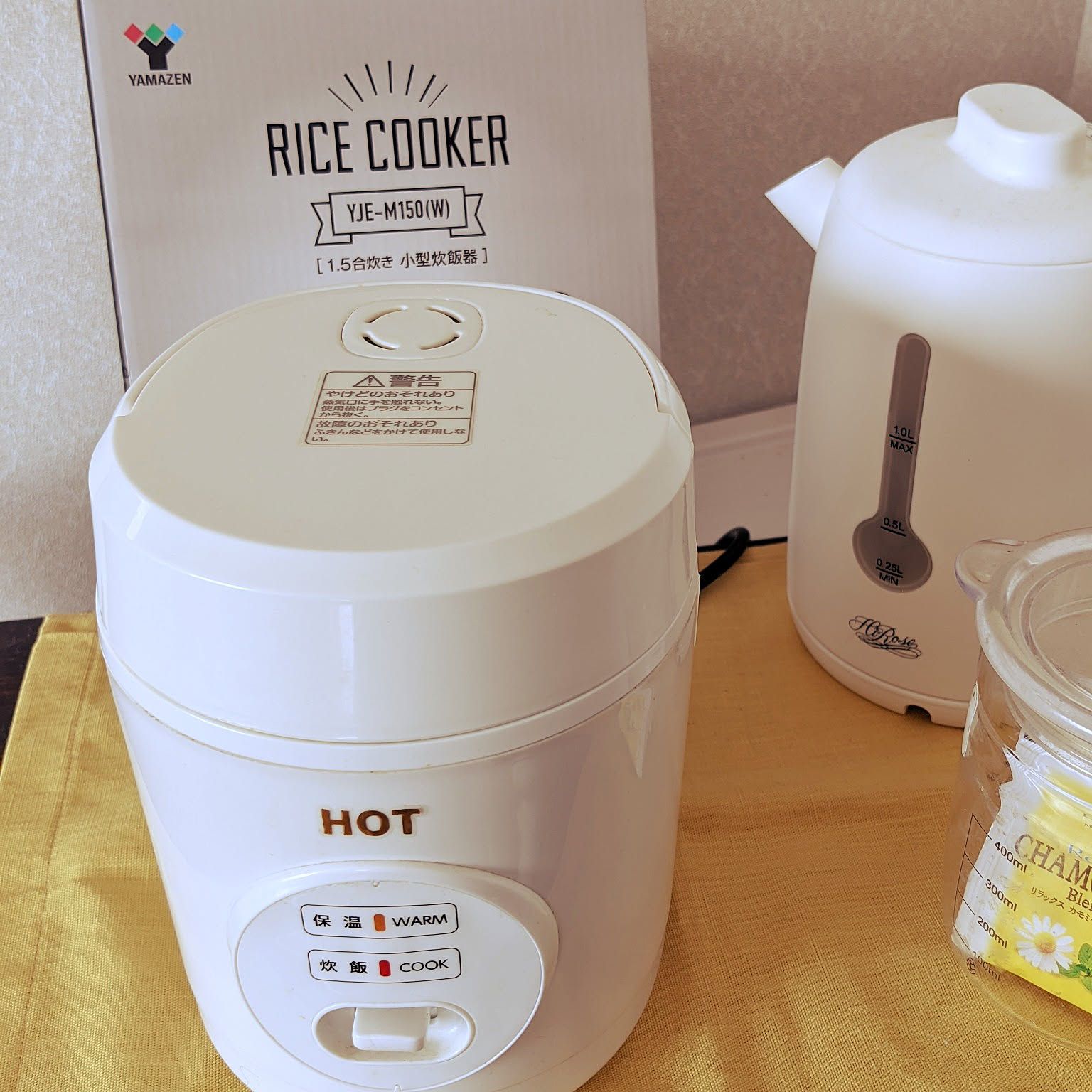 A white Yamazen 1.5-go mini rice cooker shown close-up beside its box.