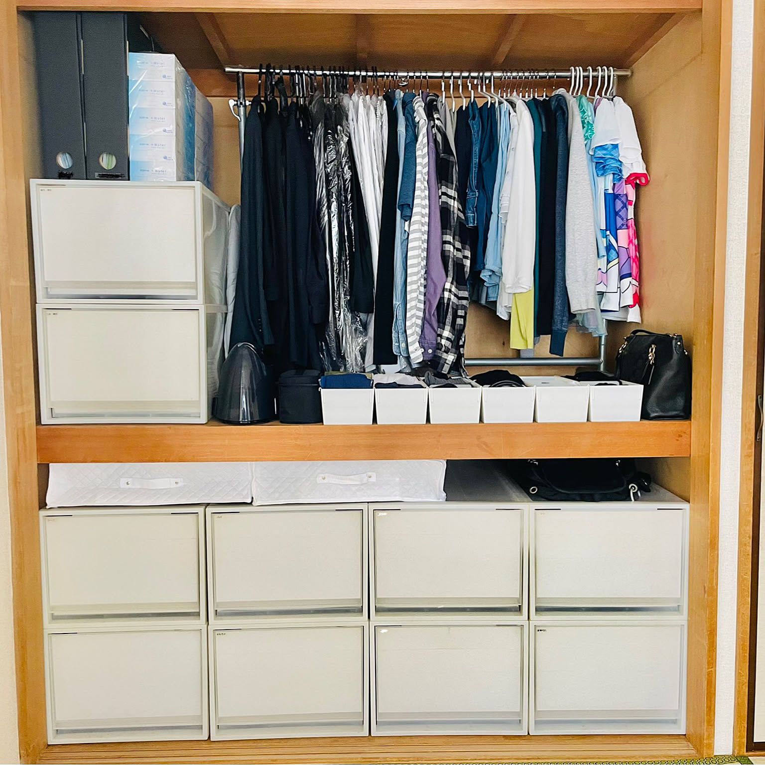 A deep Japanese closet divided into hanging clothes, small bins, drawers, and seasonal storage.