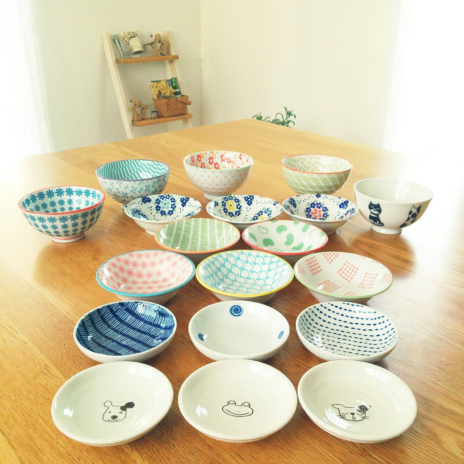 Colorful Japanese rice bowls and small plates arranged on a wooden table.