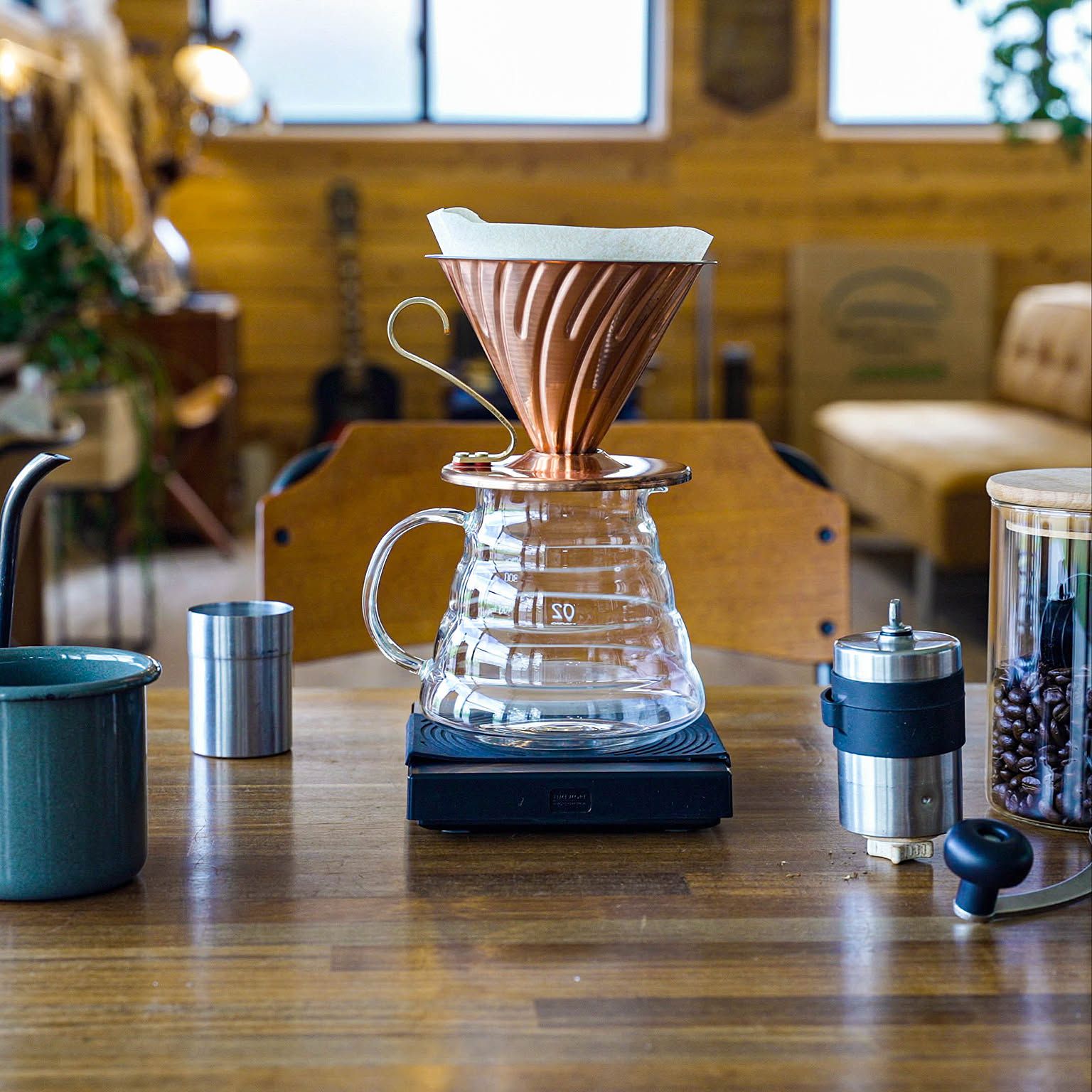 A copper HARIO V60 02 dripper set on a HARIO glass server with a hand grinder nearby.