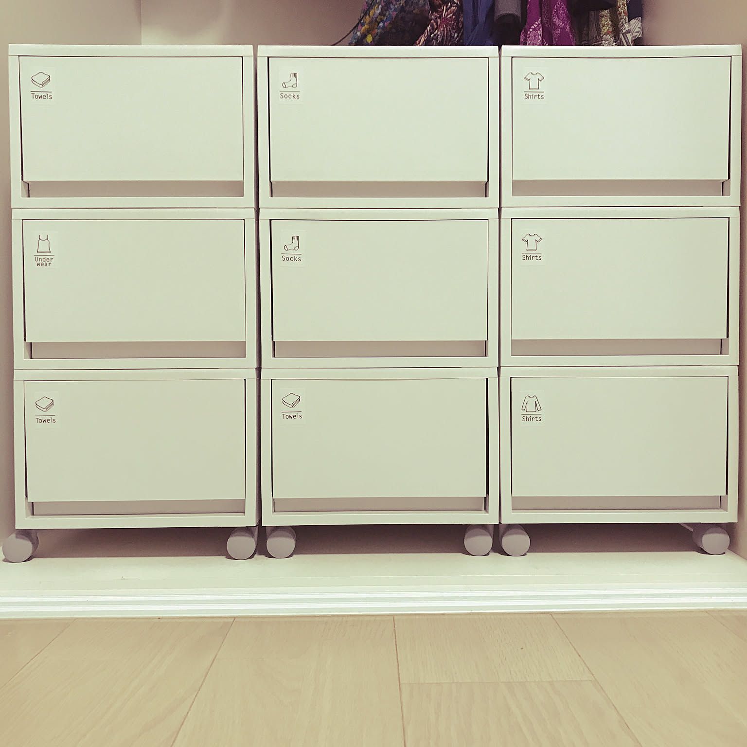 Nine white MUJI polypropylene drawers stacked three across and three high on casters, each front labeled Towels, Socks, Shirts, or Underwear.