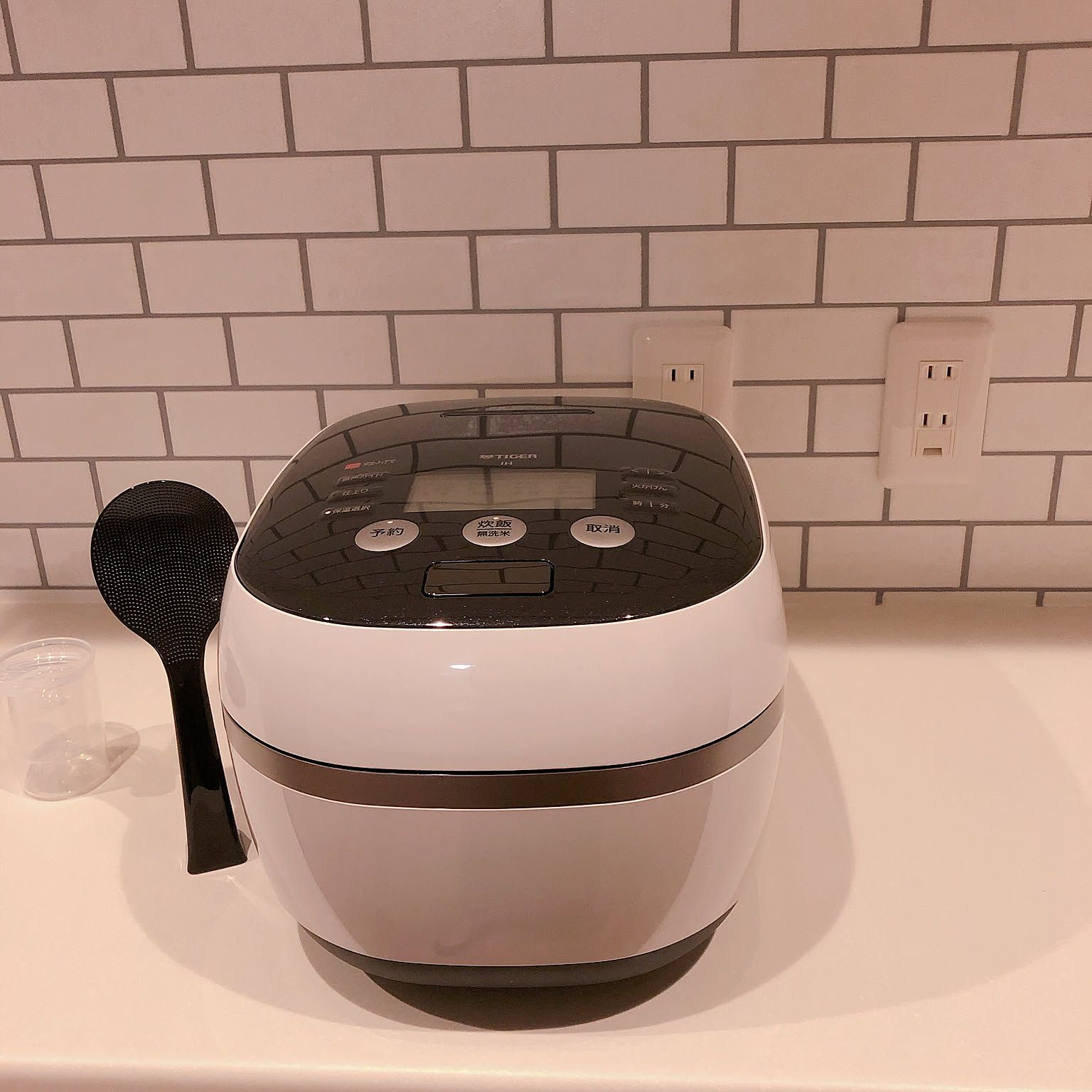 A black-and-white Tiger pressure IH rice cooker shown clearly on a kitchen counter.