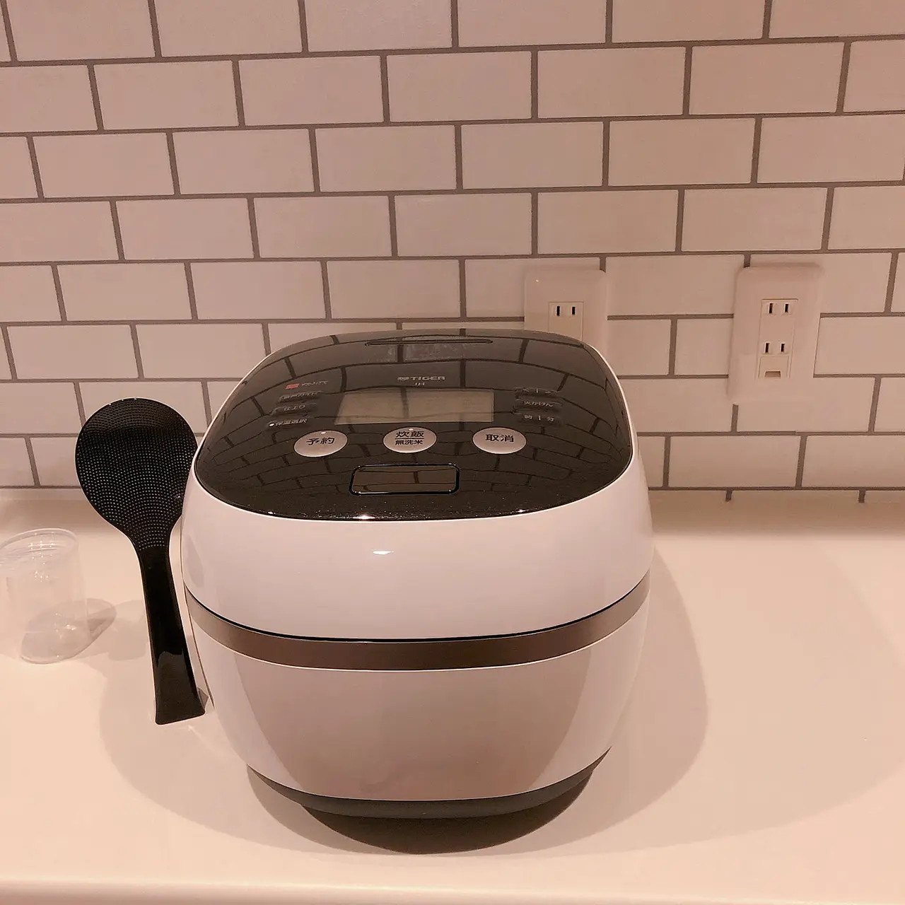 A black-and-white Tiger pressure IH rice cooker shown clearly on a kitchen counter.