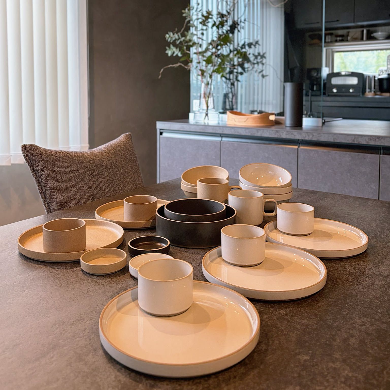 HASAMI PORCELAIN plates, bowls, mugs and a tumbler in gloss gray, white and black arranged across a dining table