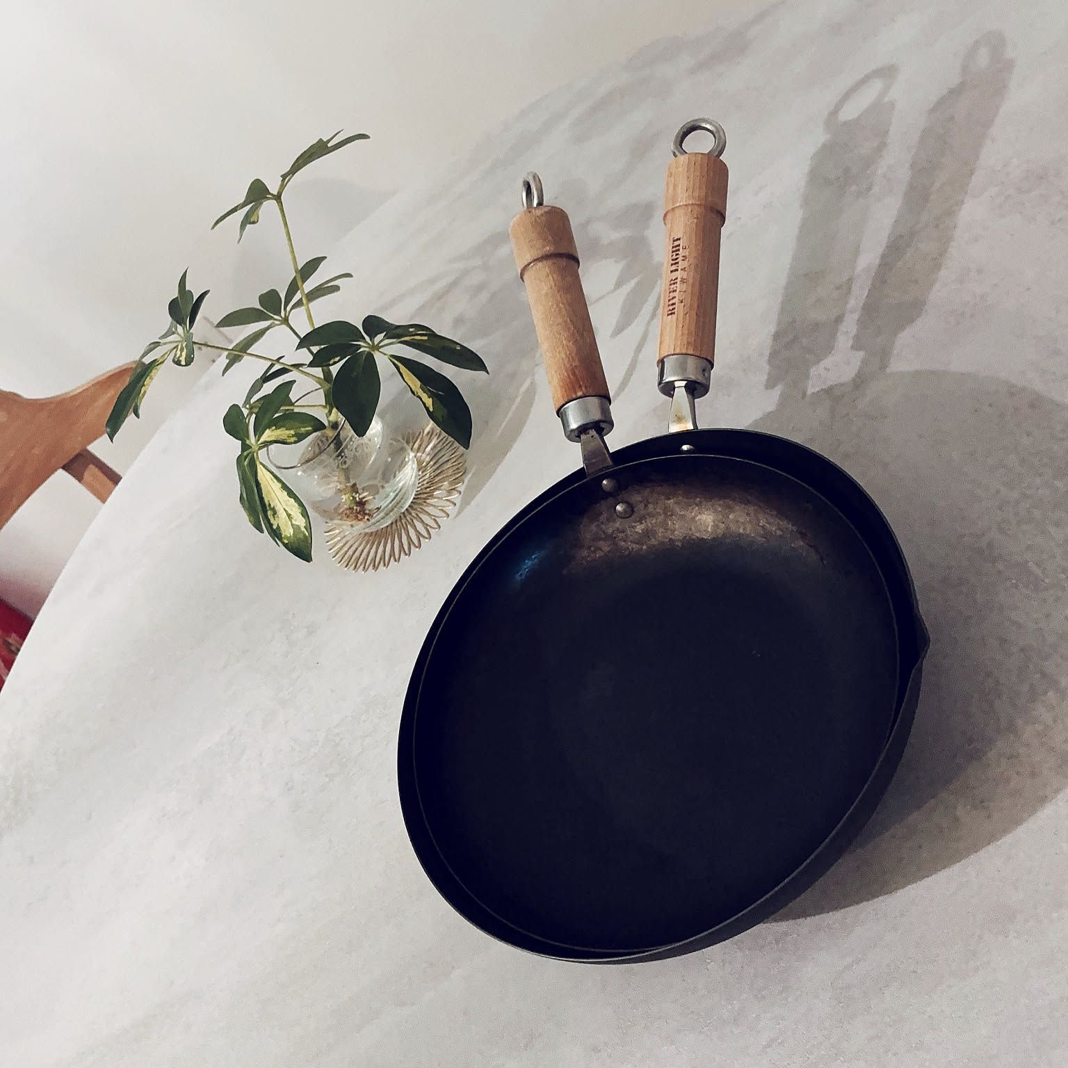 Two River Light iron frying pans with wood handles displayed against a light wall.