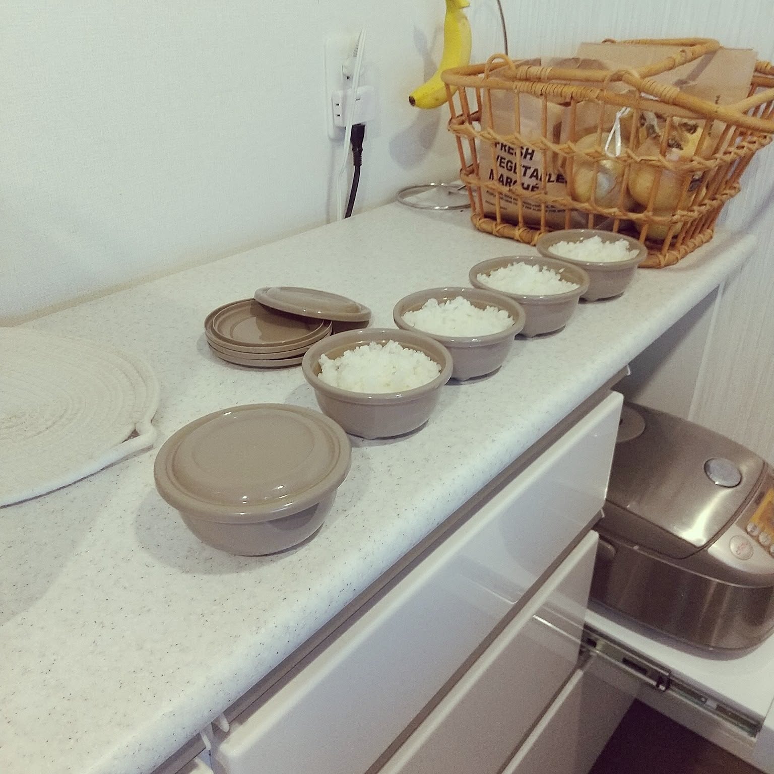 Single-serving rice containers lined up on a kitchen counter in a Japanese home, ready for storage and reheating.
