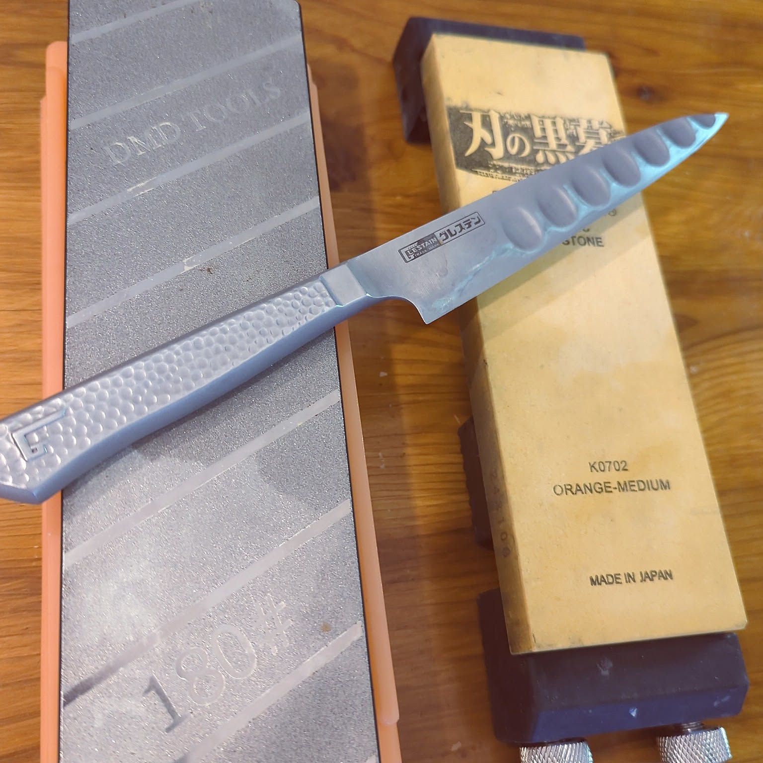 Japanese kitchen knife arranged with whetstones for sharpening and maintenance.