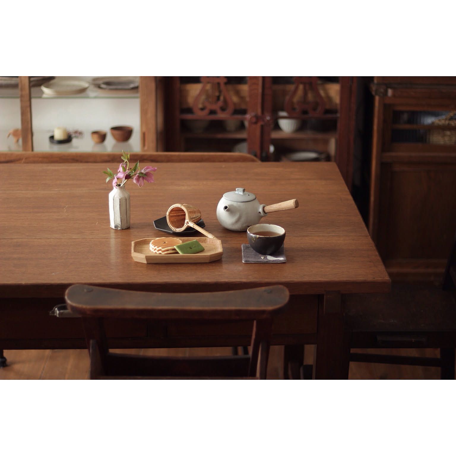 Japanese ceramic kyusu and teacup arranged on a wooden table.