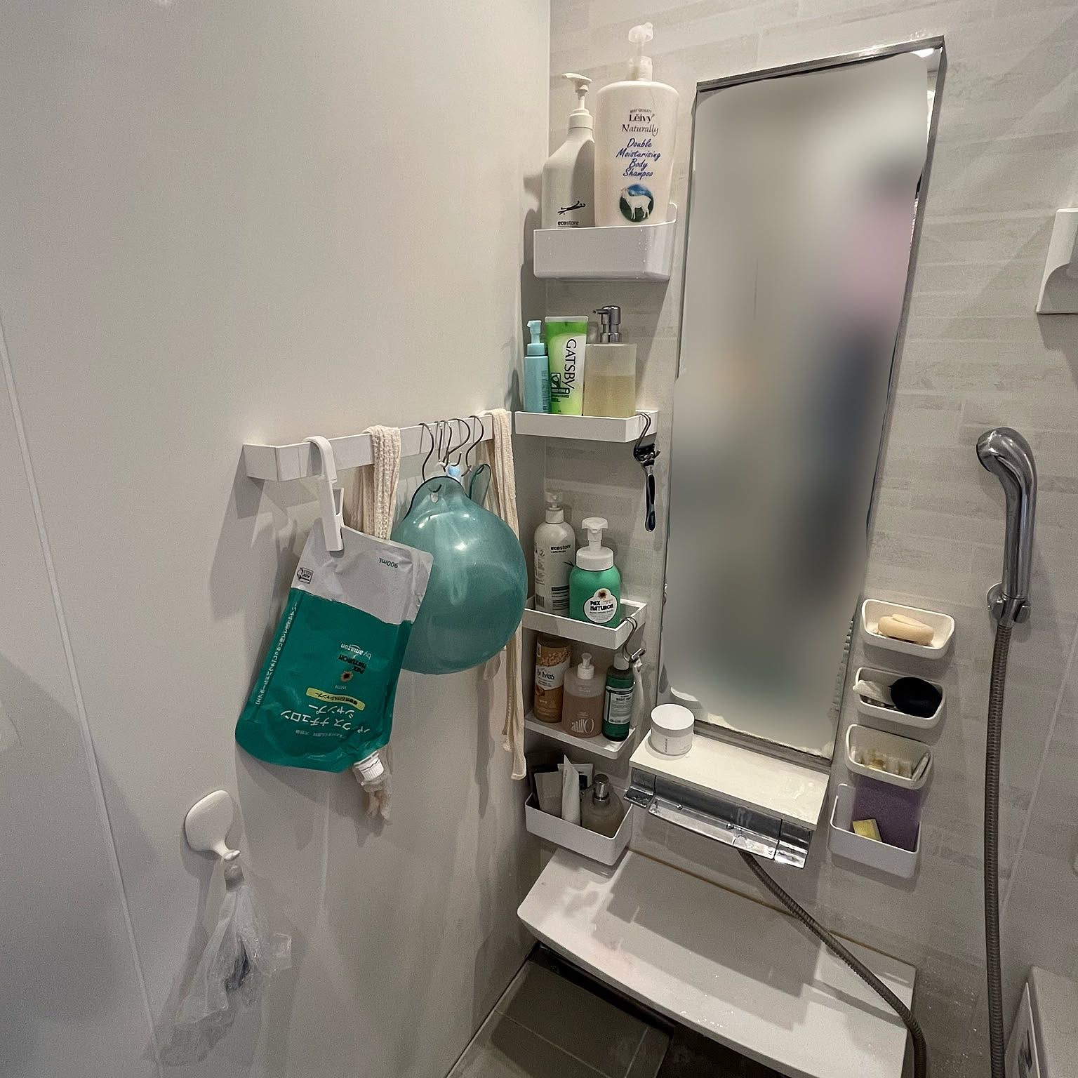 A compact Japanese bathroom using magnetic shelves, hooks, hanging refill pouches, and wall-mounted containers around the mirror.