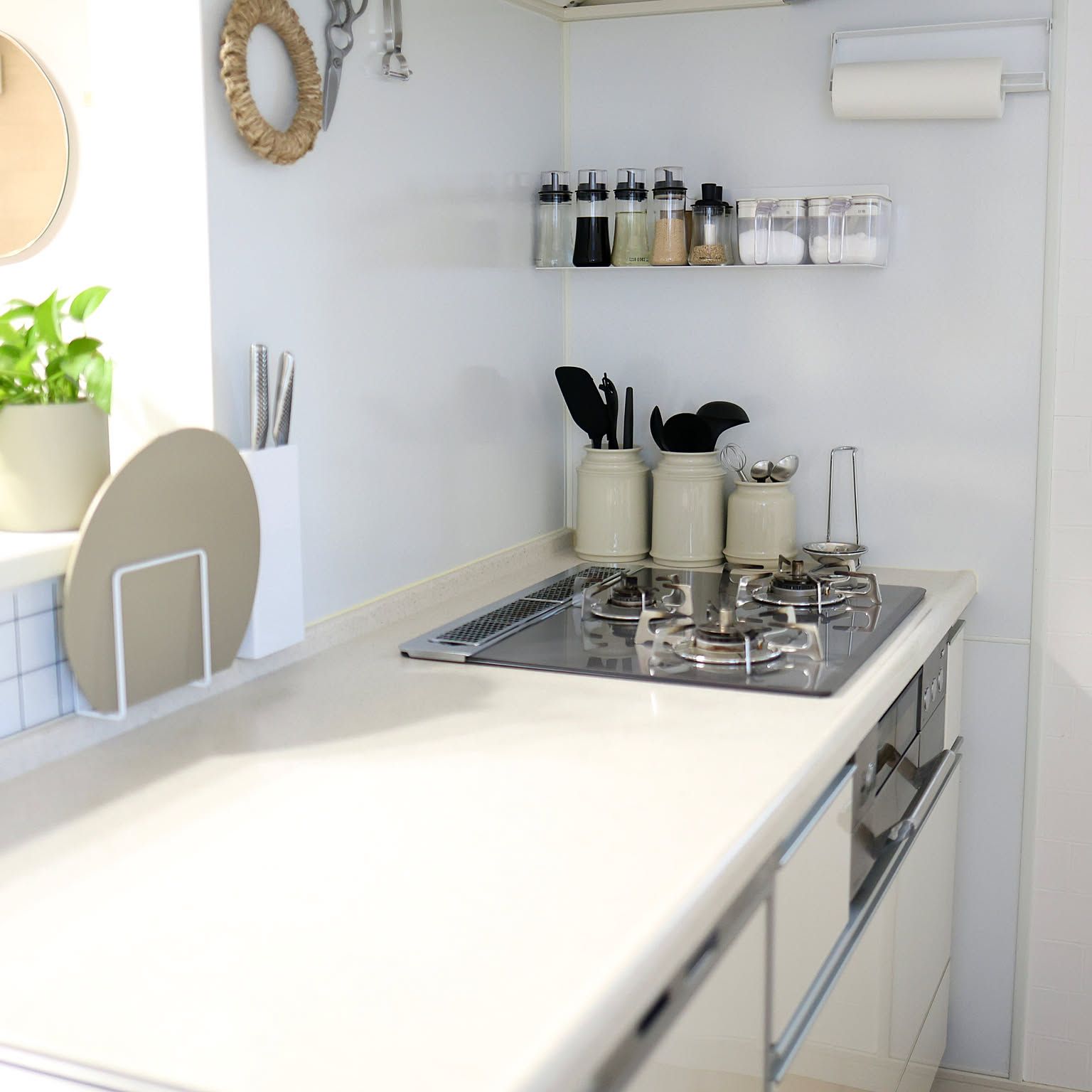 A bright Japanese kitchen counter with a steel pot-lid stand, knife stand, and magnetic wall shelf keeping the stove area clear