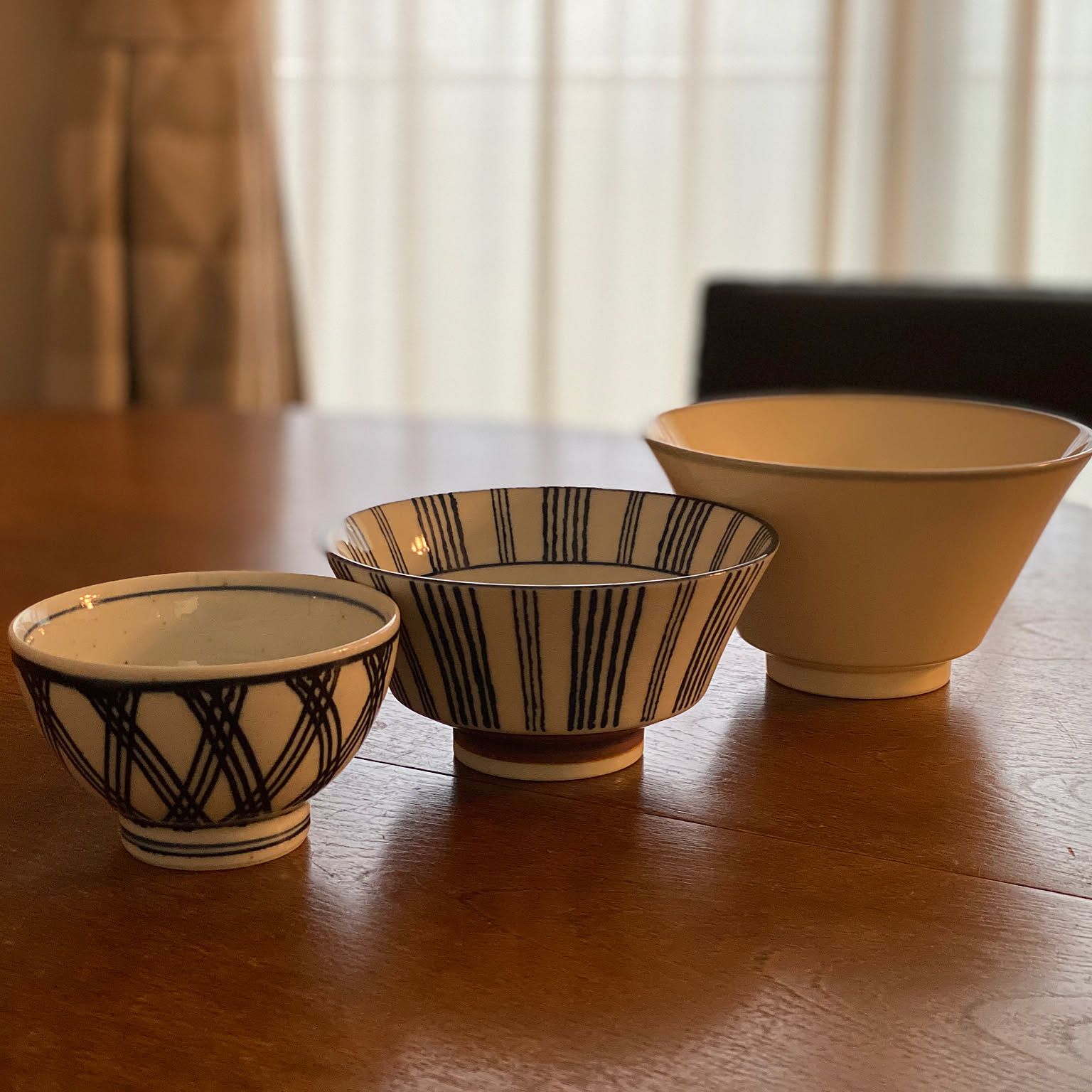 Three Japanese bowls in different sizes arranged on a wooden table.
