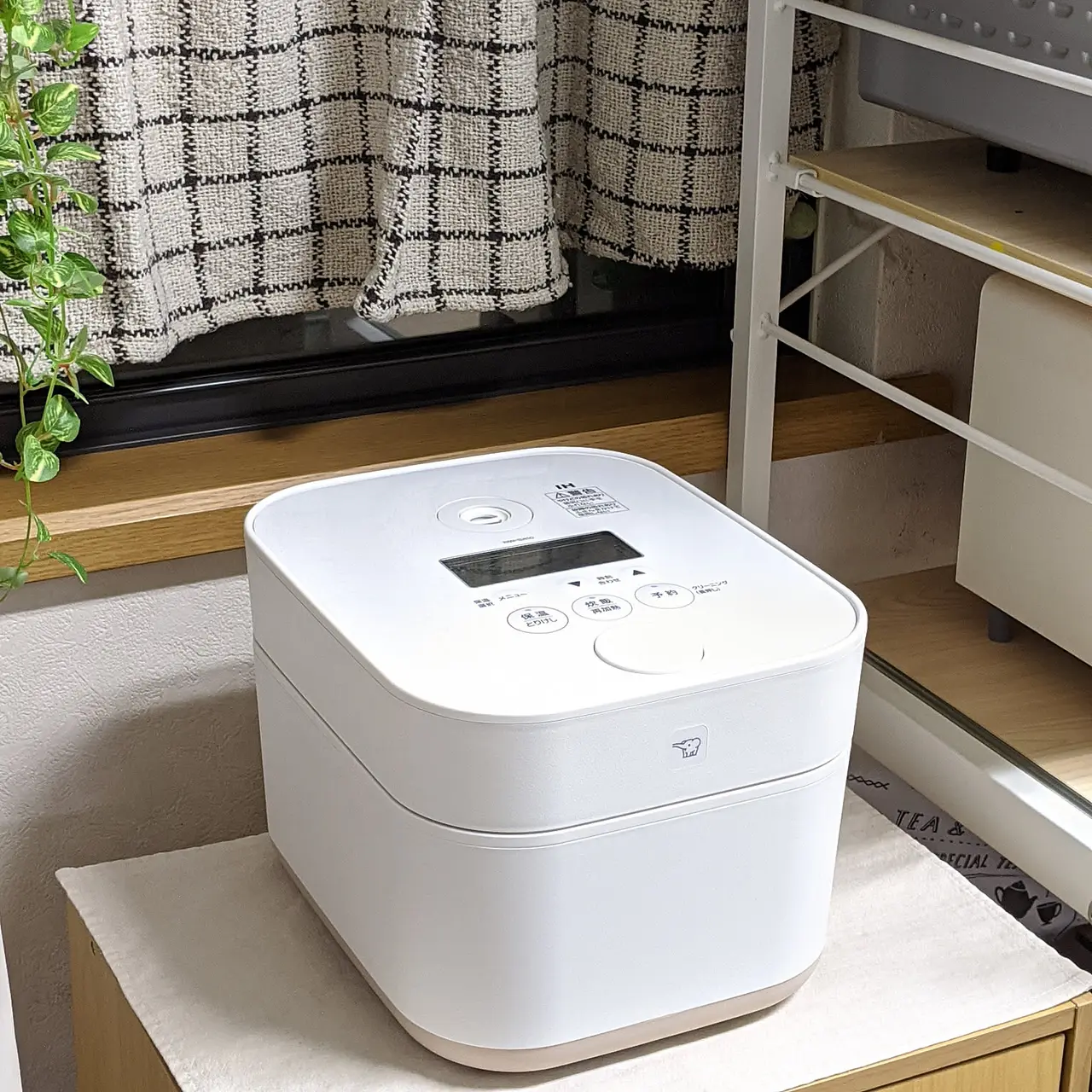 A white Zojirushi STAN. rice cooker placed neatly in a bright kitchen corner.