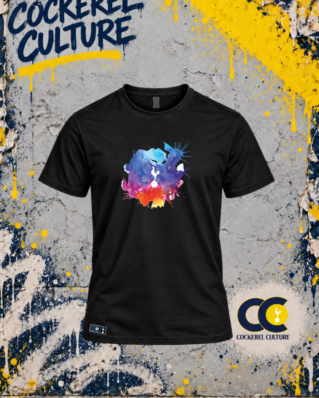A black t-shirt with the cockerel picked out of a splash of watercolour in blue, purple, pink and orange across the chest, seen from the front.