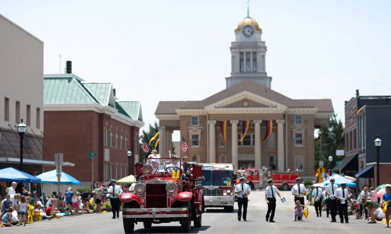 An old fire truck transporting people down the road during the Strassenfest Parade in Jasper, Indiana
