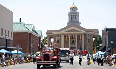 An old fire truck transporting people down the road during the Strassenfest Parade in Jasper, Indiana