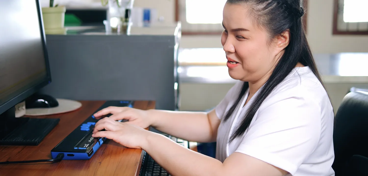 Remote worker with blindness typing on her braille keyboard.