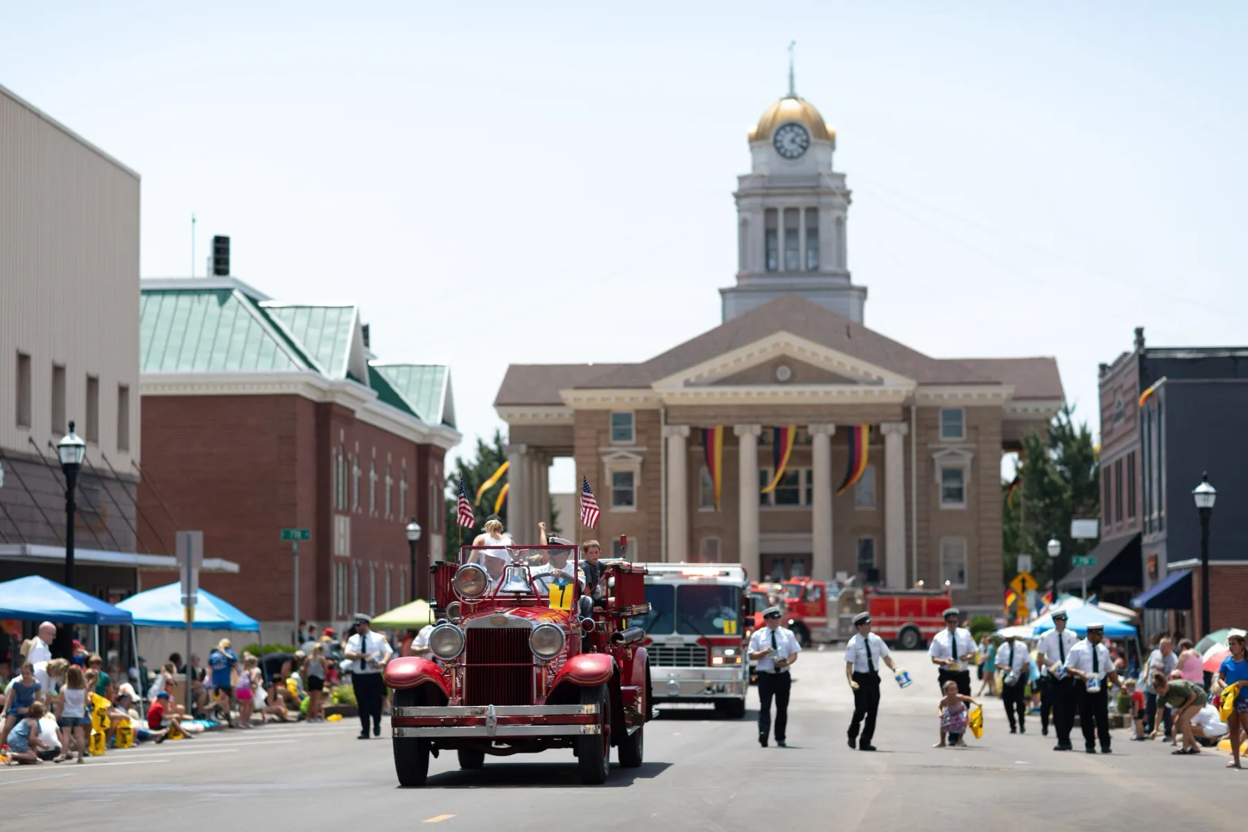 An old fire truck transporting people down the road during the Strassenfest Parade in Jasper, Indiana