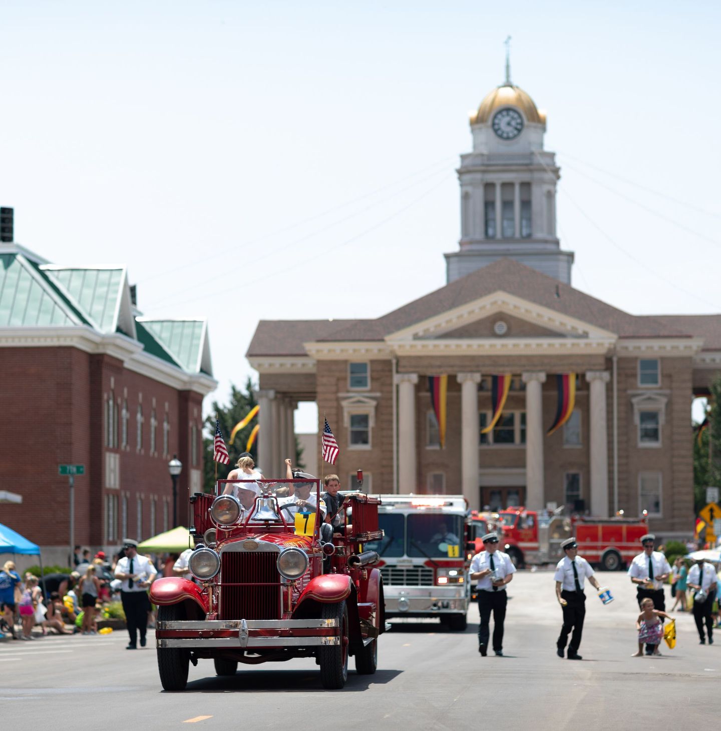 An old fire truck transporting people down the road during the Strassenfest Parade in Jasper, Indiana