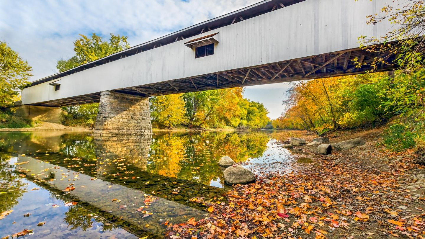 Potter's Covered Bridge crosses the West Fork of the White River surrounded by colorful fall foliage in Noblesville, Indiana.