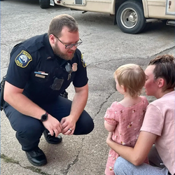 Jackson Police Department officer interacting with Jackson citizen and young child.