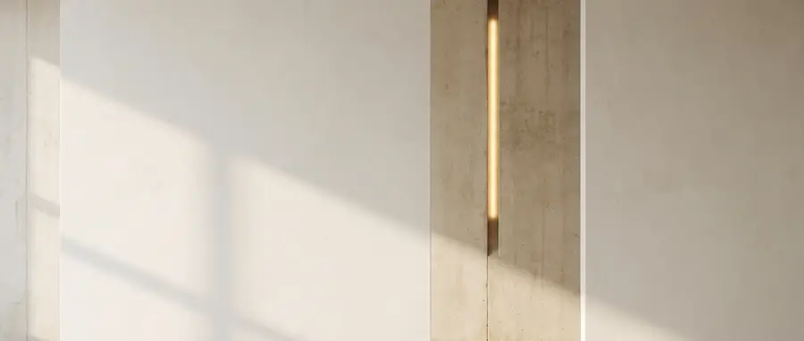 A bare plaster wall in raking daylight, a slim vertical recess lit warm gold