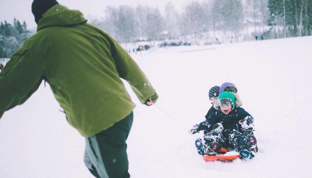 Barn som blir dratt på akebrett i snøen.
