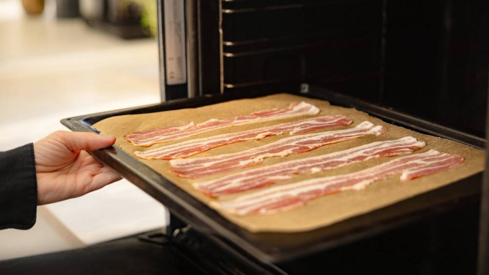 Bacon som settes i ovnen for å stekes.