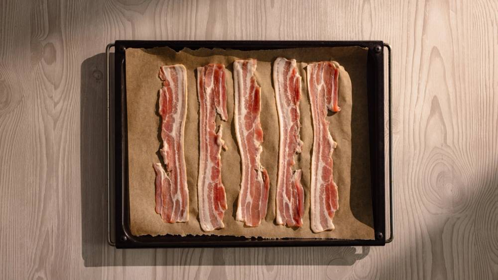 Bacon på stekebrett før det skal stekes i ovnen.