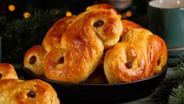 Lussekatter i en bolle på bord med kaffekopper.