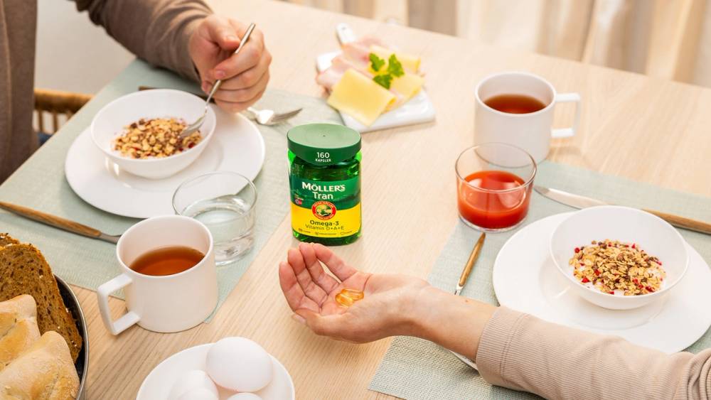 Personer som spiser frokost og tar Möllers Tran omega-3 piller.