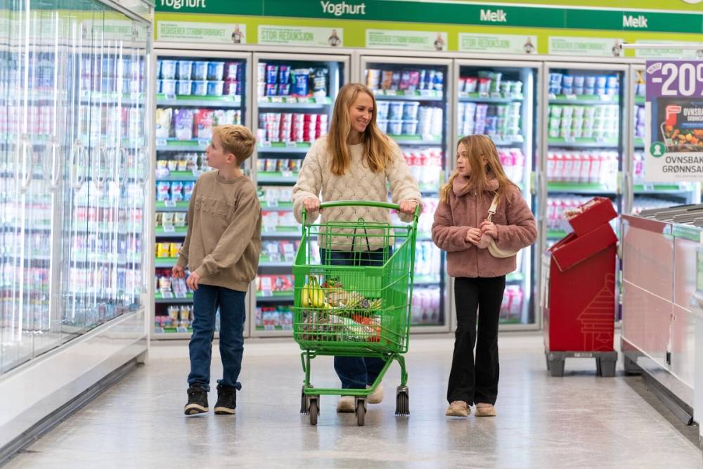 Mor og barn med handlevogn i KIWI-butikk.